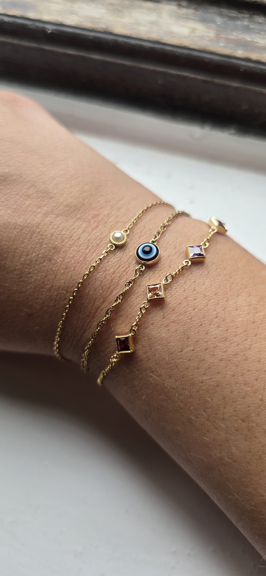 Three fine gold-coloured bracelets with decorative charms